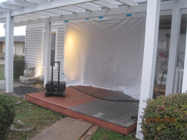 Photo from exterior of a home in an asbesotos remediation project overseen by Precision Environmental Services. Porch is shown and door opening is covered in plastic sheeting.